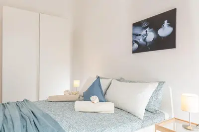 a white bedroom with a bed with blue and white pillows at Bell Appartamento in Rome