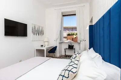 a white bedroom with a large bed and a desk at Portico d'Ottavia LUX in Rome