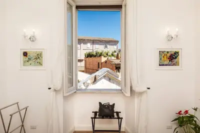 a window in a white room with a chair looking out at Portico d'Ottavia LUX in Rome