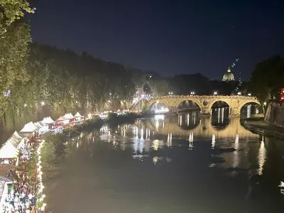 a bridge over a river at night with lights at Delizioso appartamento San Pietro in Rome