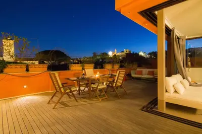 a table and chairs on a deck at night at Pelliccia 11 Trastevere Penthouse in Rome