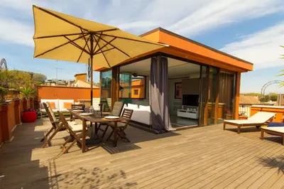 a wooden deck with a table and an umbrella at Pelliccia 11 Trastevere Penthouse in Rome