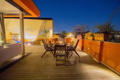 a patio with a table and chairs on a balcony at Pelliccia 11 Trastevere Penthouse in Rome