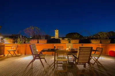 a table and chairs on a deck at night at Pelliccia 11 Trastevere Penthouse in Rome