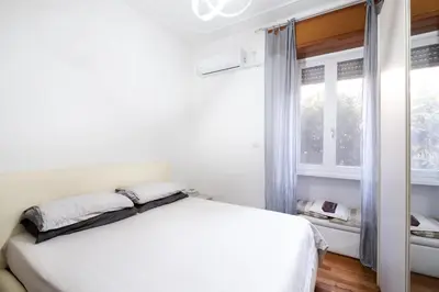 a white bedroom with a bed and a window at Appio11 Apartment in Rome