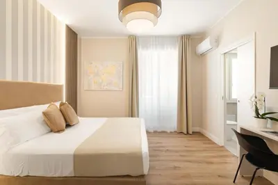 a bedroom with a white bed and a desk and a window at AlbaDea Deluxe in Rome