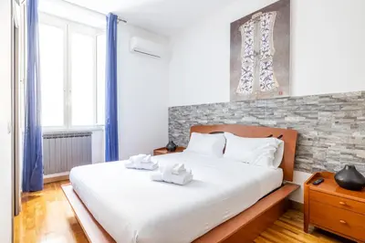 a bedroom with a large white bed with blue curtains at VG [ROME CENTER] Double Room in Rome