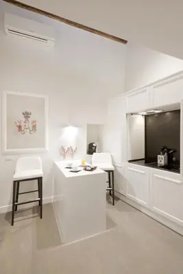 a white kitchen with two white chairs and a counter at Carthusia Suites Roma in Rome