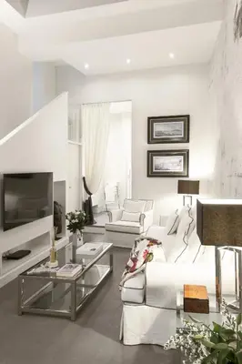 a white living room with a white couch and a tv at Carthusia Suites Roma in Rome