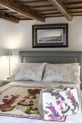 a bed with two pillows and a picture on the wall at Carthusia Suites Roma in Rome