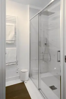 a white bathroom with a shower and a toilet at Carthusia Suites Roma in Rome