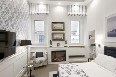 a bedroom with a fireplace and a bed and a chair at Carthusia Suites Roma in Rome