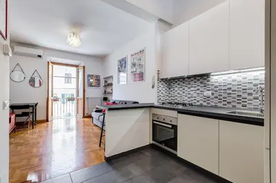 a kitchen with white cabinets and black counter tops at AM House Colosseo in Rome