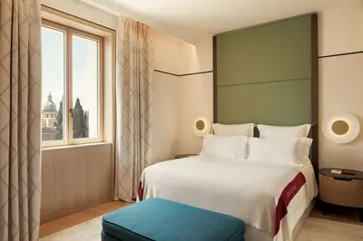 a bedroom with a large white bed and a yellow wall at Bvlgari Hotel Roma in Rome