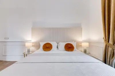 a bedroom with a white bed with two orange pillows at Monti Suites Cavour in Rome