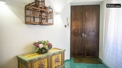 a vase of flowers on a dresser next to a door at Foscari Holiday House in Rome