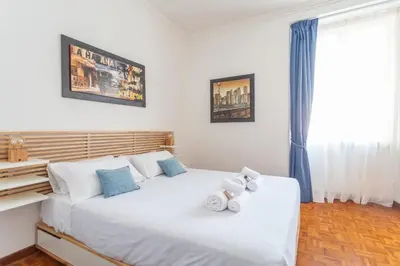 a bedroom with a large white bed with blue accents at Modern 2BDR apartment vibrant Prati neighborhood in Rome