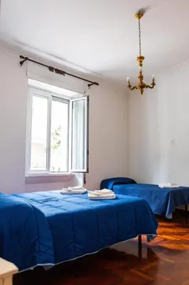 a room with two blue beds and a window at Alexander Vatican House in Rome
