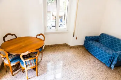 a living room with a wooden table and a blue couch at Alexander Vatican House in Rome