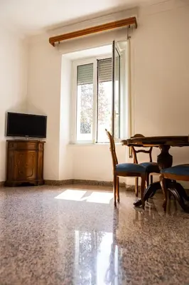 a living room with a table and chairs and a window at Alexander Vatican House in Rome