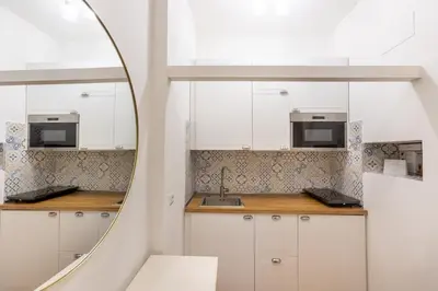 a kitchen with white cabinets and a mirror at Vatican Vita Apartment in Rome
