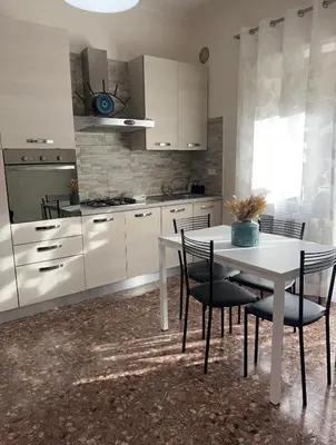 a kitchen with white cabinets and a table and chairs at Casa Arya in Rome