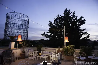 a patio with white chairs and tables and a tree at TIBERIVS Home in Rome