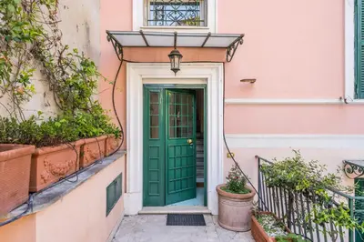 a green door on a pink building with potted plants at Elizabeth Penthouse, Charmy Apartment in Little London 10 Min From the Center in Rome