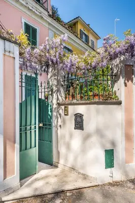 a house with a green door and purple flowers on a fence at Elizabeth Penthouse, Charmy Apartment in Little London 10 Min From the Center in Rome