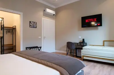 a bedroom with two beds and a tv on the wall at Hotel AD Suites Nazionale in Rome