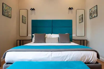 a large bed with a blue headboard and two mirrors at Hotel AD Suites Nazionale in Rome