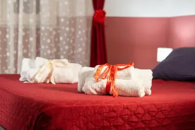 three towels on a bed with a red table at HolidayHomeNazzarena in Rome
