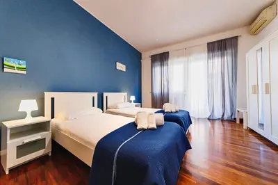 two beds in a bedroom with blue walls and wooden floors at Monferrato Home in Rome